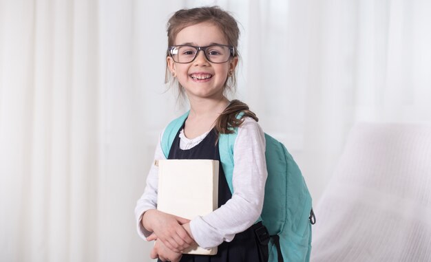 Girl-elementary school student with a backpack and a book