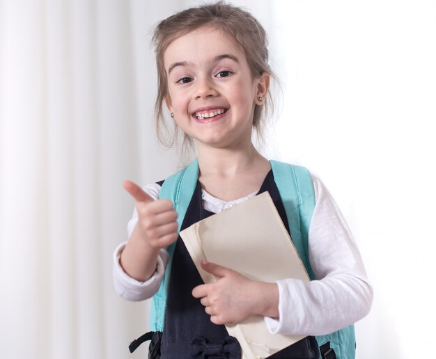 Girl-elementary school student with a backpack and a book