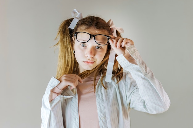 Girl in eyeglasses holding her hair looking at camera