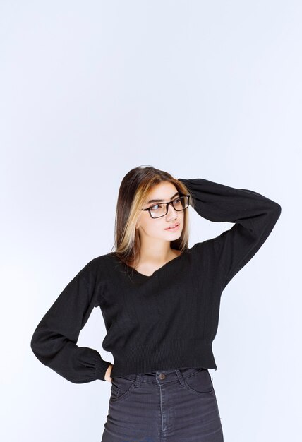 Girl in eyeglasses looks thoughtful and hesitating.