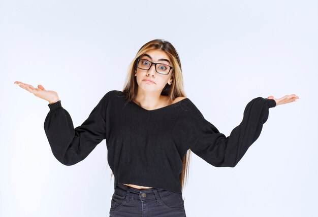 Girl in eyeglasses looks unexperienced and confused.