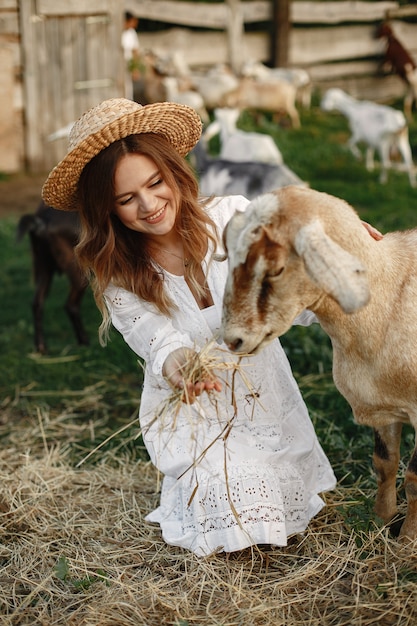 Free photo girl farmer with white goat. woman and small goat green grass. eco farm. farm and farming concept. village animals. girl play cute goat. f