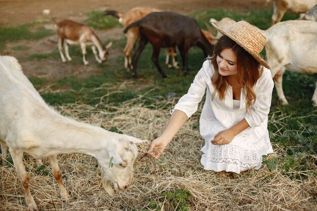 Girl farmer with white goat. Woman and small goat green grass. Eco farm. Farm and farming concept. Village animals. Girl play cute goat. F