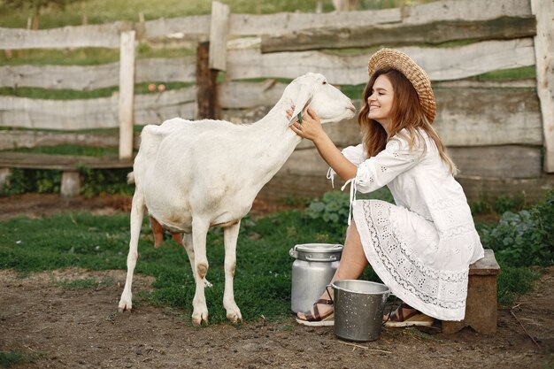 Girl farmer with white goat. Woman and small goat green grass. Eco farm. Farm and farming concept. Village animals.