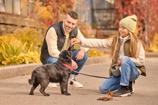 犬に餌をやる女の子、隣に座っているお父さん