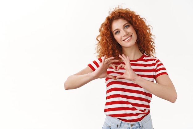 Foto gratuita ragazza sentimento amore affetto mostra fidanzato cuore segno sorridente sciocco testa inclinabile ghignante sguardo commosso contemplando bella scena delicata in piedi sfondo bianco felice grato bel gesto