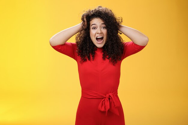 Girl feeling pressure standing anxious in panic holding hands on curly hair yelling at camera distur...