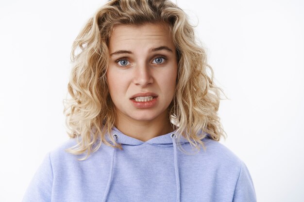 Girl feels sorry and upset expressing empathy, looking concerned with sorrow in eyes apologizing awkward and sad, standing insecure and unconfident, trying say important words over white wall