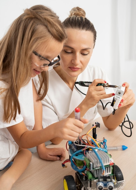 Girl and female teacher doing science experiments with robotic car