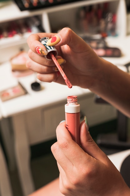 Girl filling brush with gloss