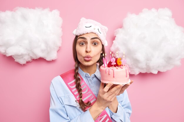 girl finally has birthday keeps lips folded wants to kiss boyfriend being thankful for gift holds tasty cake wears sleepmask and shirt accepts congratulations