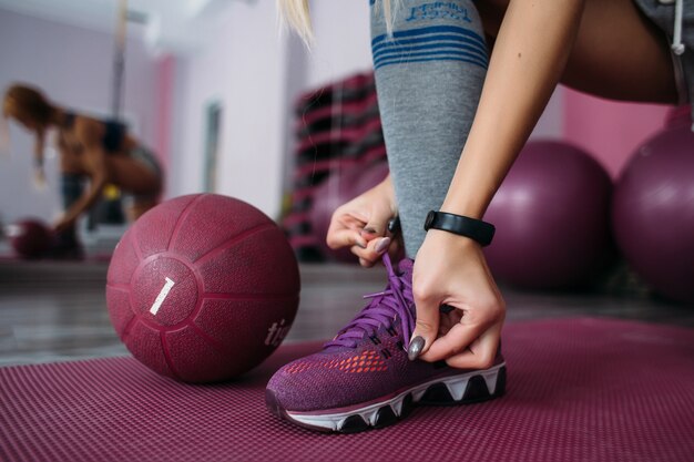 Girl fixes her violet snickers before the training in a gym