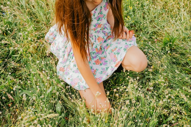 Girl in floral dress sitting in field