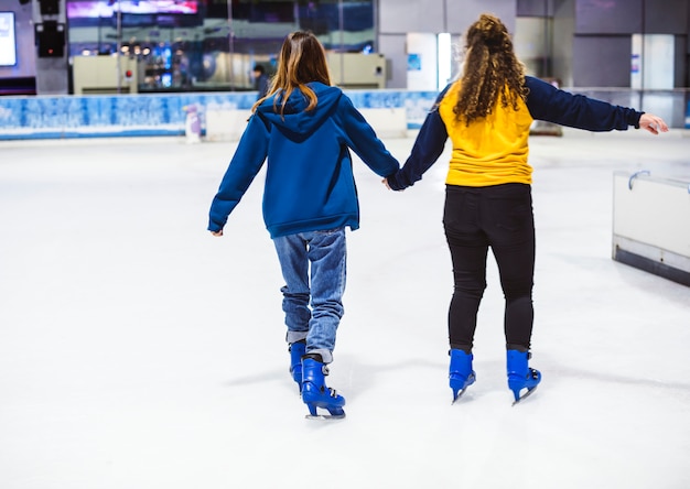 Free photo girl friends ice skating on the ice rink together