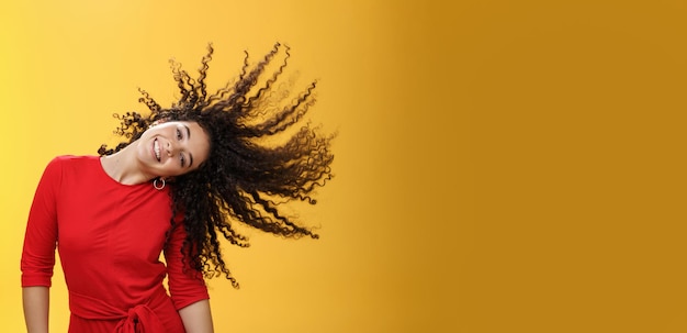 Foto gratuita ragazza che ottiene i capelli ondeggianti spensierati e selvaggi e fa il sole con i riccioli che volano in aria sorridendo ampiamente t