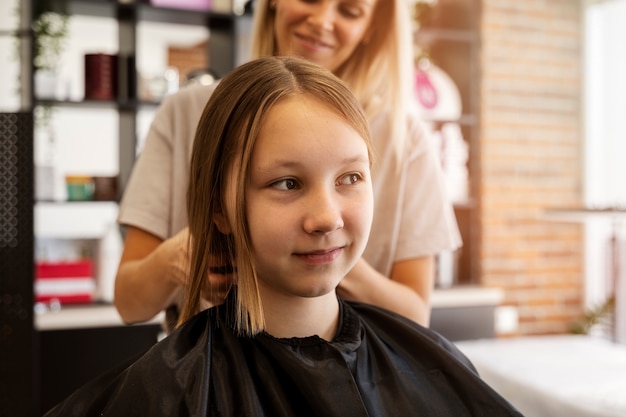 Free photo girl getting hair styled at salon side view