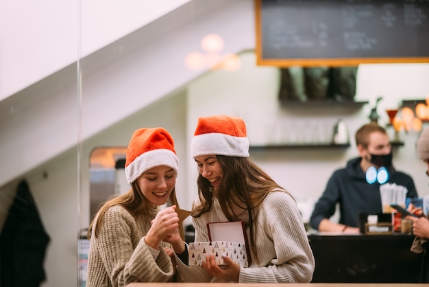 The girl gives a gift to her female friend in caffe