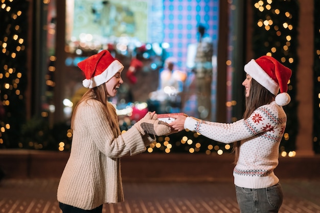 Free photo the girl gives a gift to her female friend on the street