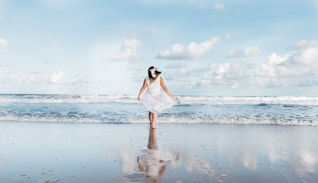 Girl going out of the sea wearing white clothes 