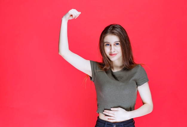 Free photo girl in green shirt demonstrating her arm muscles.