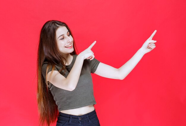 Free photo girl in green shirt pointing at something above.