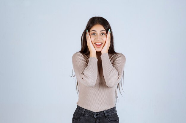 Girl in grey shirt looks excited and surprized. 