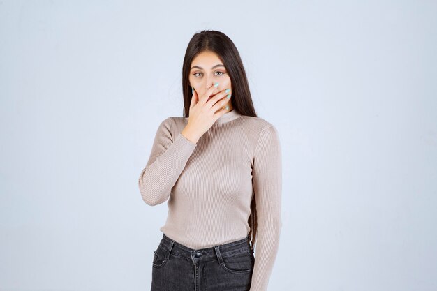 Girl in grey shirt looks scared and afraid. 