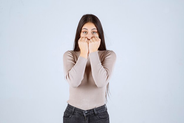 Girl in grey shirt looks scared and afraid. 