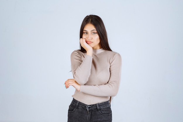 Girl in grey shirt looks thoughtful and confused. 