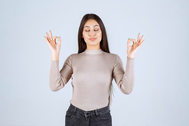 Foto gratuita ragazza in camicia grigia che fa meditazione.