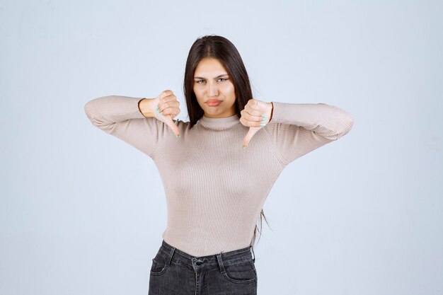 Girl in grey shirt making thumb down sign. 