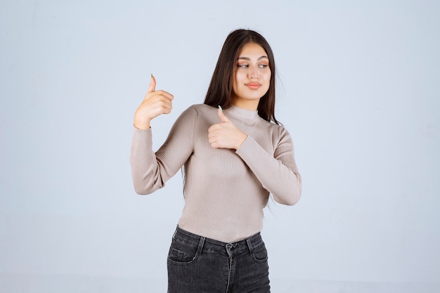 Girl in grey shirt making thumb up sign. 