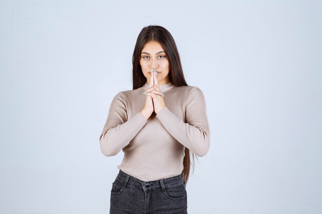 Girl in grey shirt pointing her head and thinking. 