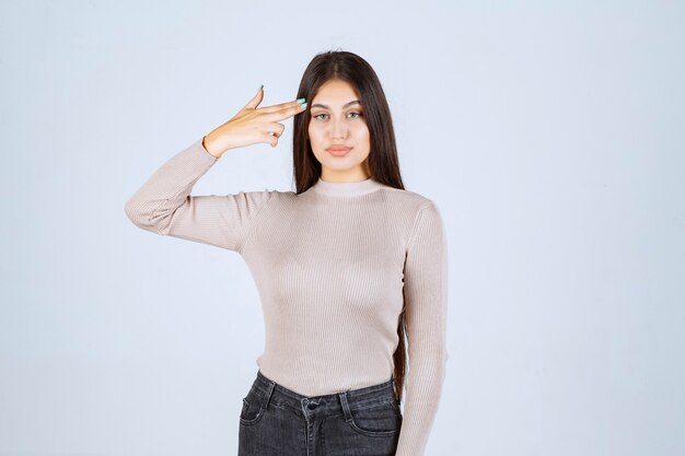 Girl in grey shirt pointing her head and thinking. 