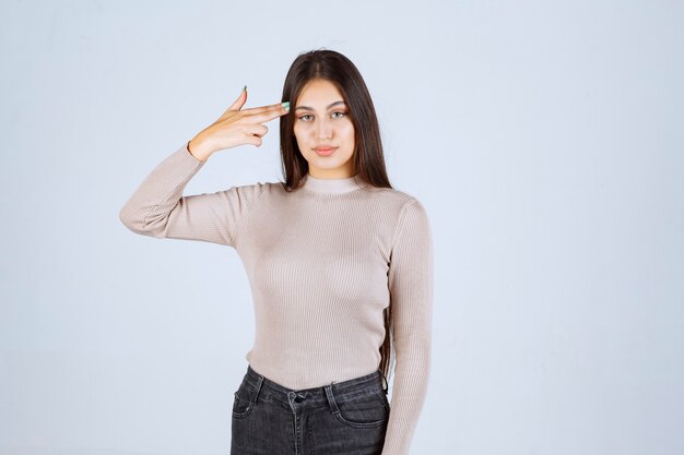 Girl in grey shirt pointing her head and thinking. 