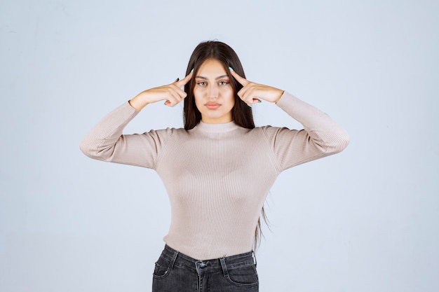 Ragazza in camicia grigia che punta la testa e il pensiero.