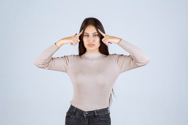 Girl in grey shirt pointing her head and thinking. 