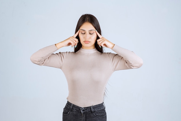 Girl in grey shirt pointing her head and thinking. 