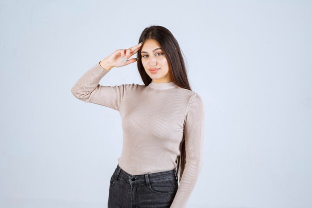 Girl in grey shirt pointing her head and thinking. 