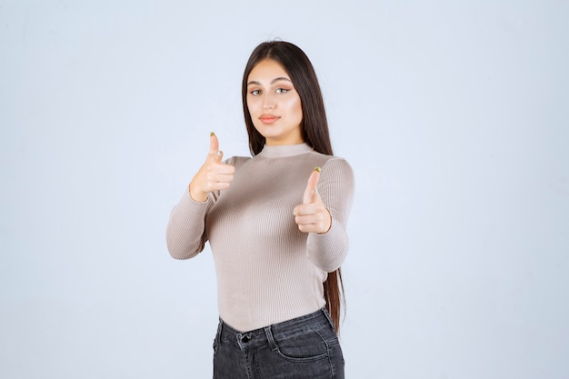 Girl in grey shirt pointing to someone ahead. 