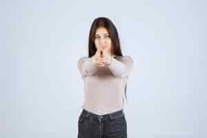 Free photo girl in grey shirt pointing to someone ahead.