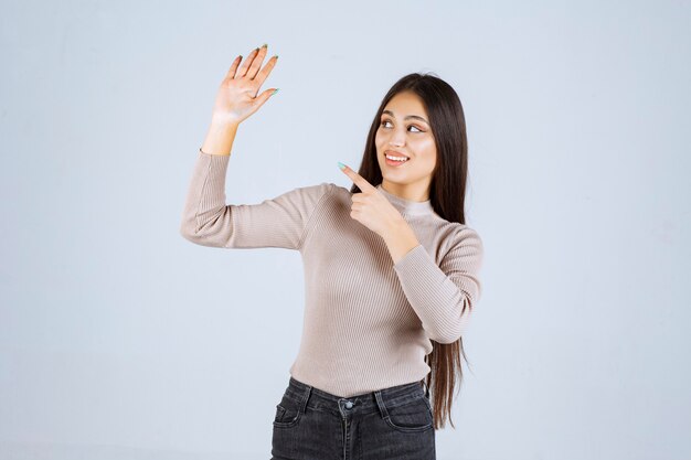 Girl in grey shirt raising her hands up. 