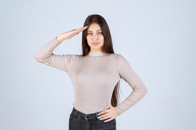 Girl in grey shirt saluting like a soldier. 