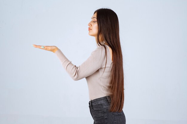 Girl in grey shirt showing the estimated measures of an object. 