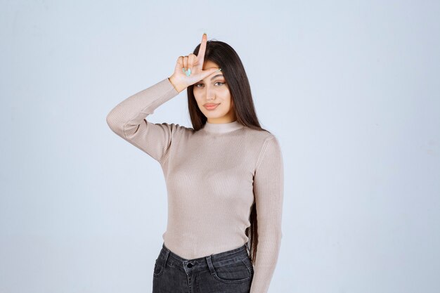 Free photo girl in grey shirt showing loser hand sign.