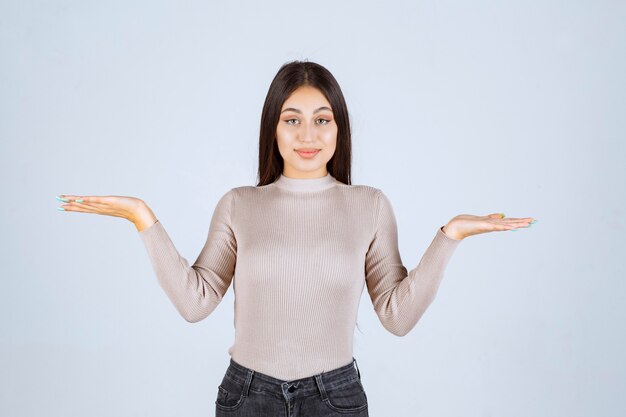 Girl in grey shirt showing something in her hand. 