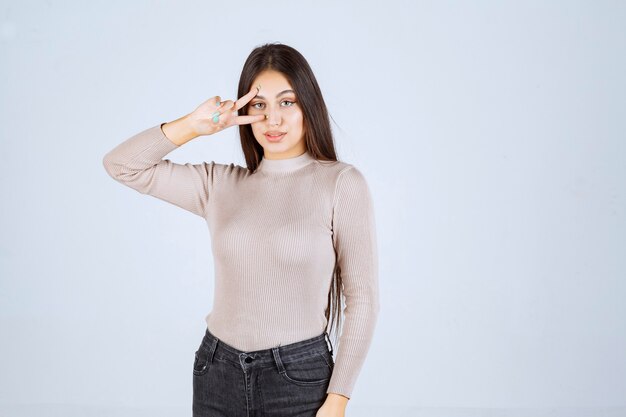 Girl in grey sweater doing peace hand sign