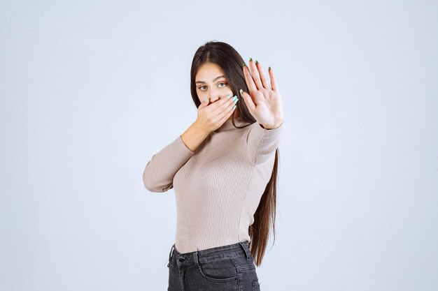 Girl in grey sweater feels bad smell and covering nose. 