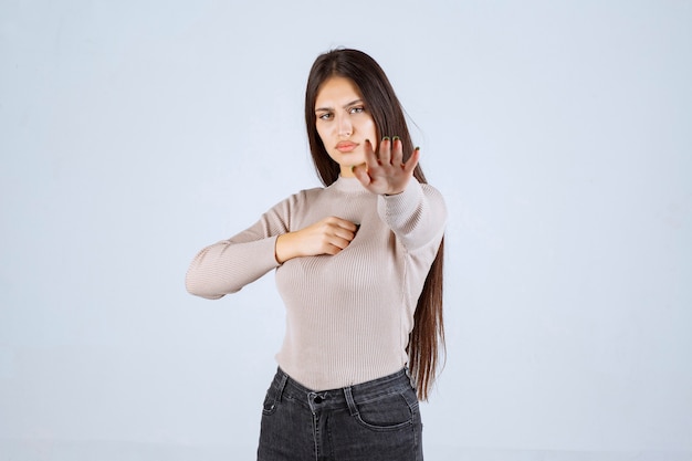 Ragazza in maglione grigio che dà pose cattive e seducenti.