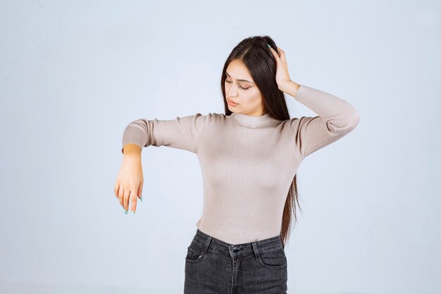 Girl in grey sweater holding her face and head. 